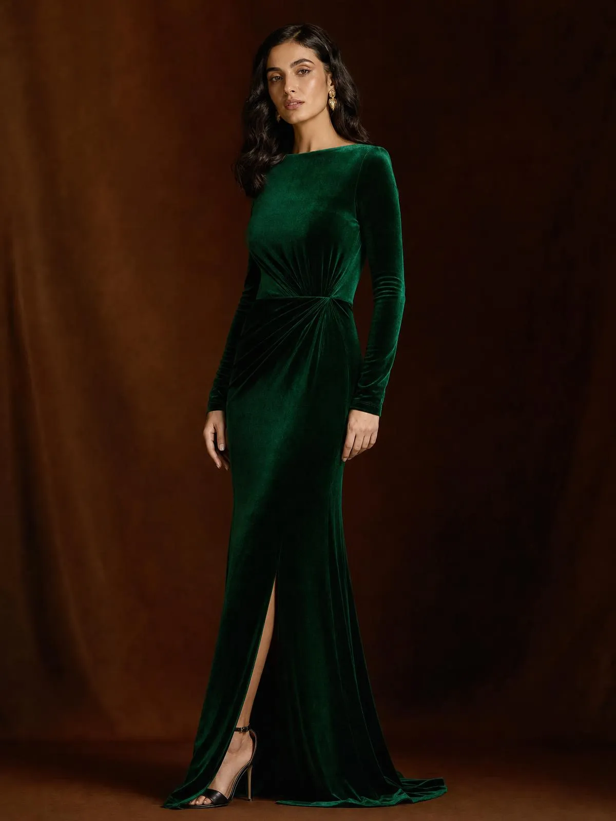 Frau in einem smaragdgrünen Samt-Abendkleid mit schmaler Silhouette vor dunklem Studiohintergrund