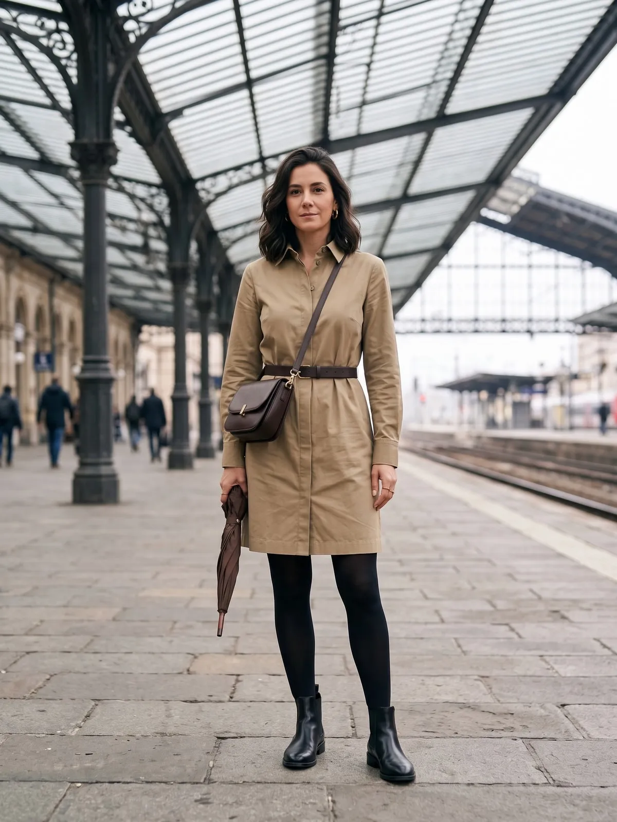 Schwarze Chelsea Boots aus Leder zu einem khakifarbenen Hemdblusenkleid mit Gürtel und blickdichter schwarzer Strumpfhose unter einem Bahnhofsdach